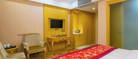 A hotel room with a bed, a desk, a chair, a television, and a wardrobe.