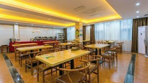 A spacious dining area with multiple tables and chairs, a buffet setup, and a large window with curtains.