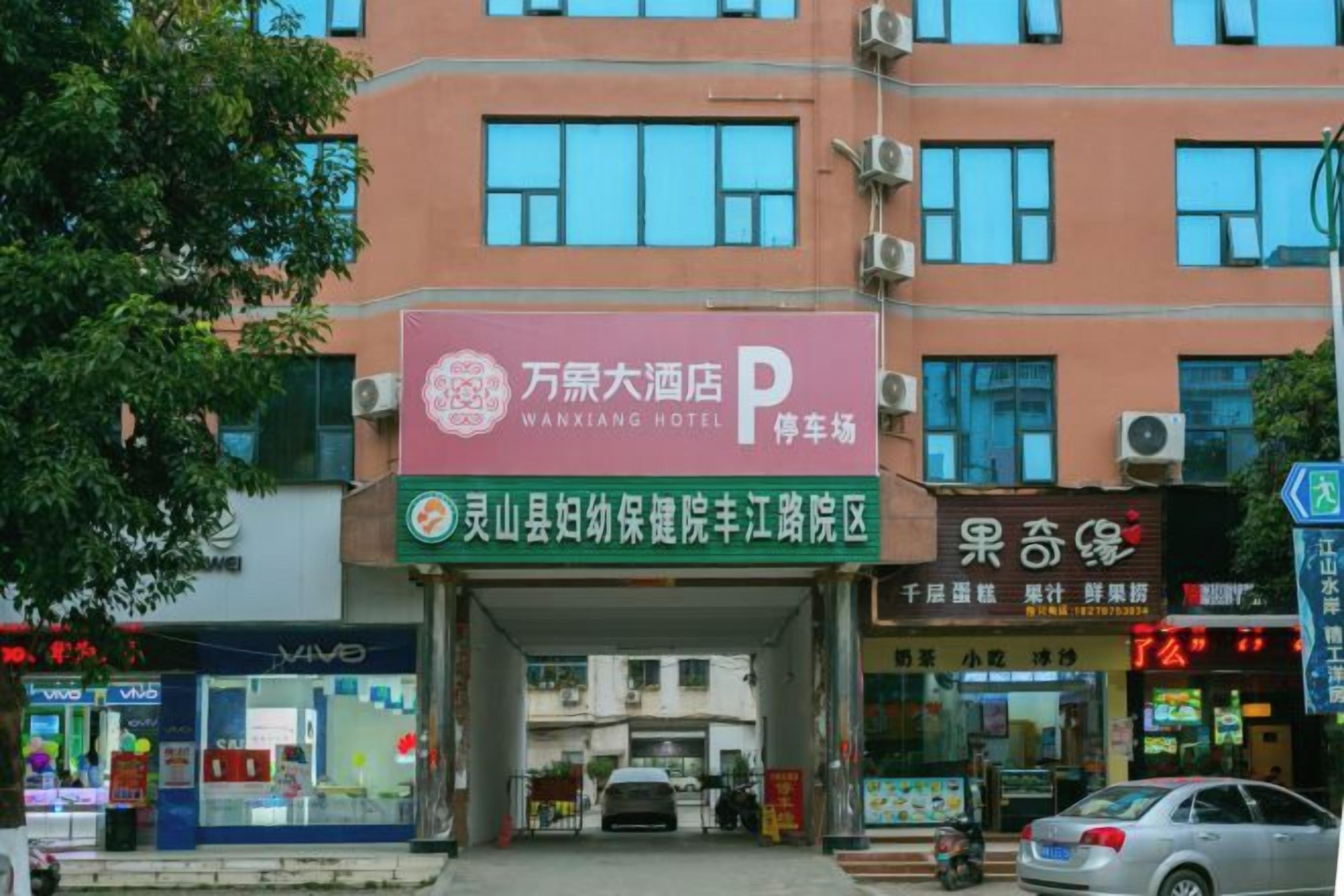 A hotel entrance with a sign for Wanxiang Hotel, a parking area, and a storefront with Chinese characters.