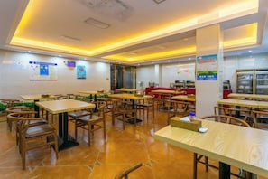 A restaurant with multiple tables and chairs, a counter, and a tiled floor. - Wanxiang Hotel (Qinzhou Lingshan) (Lingshan)