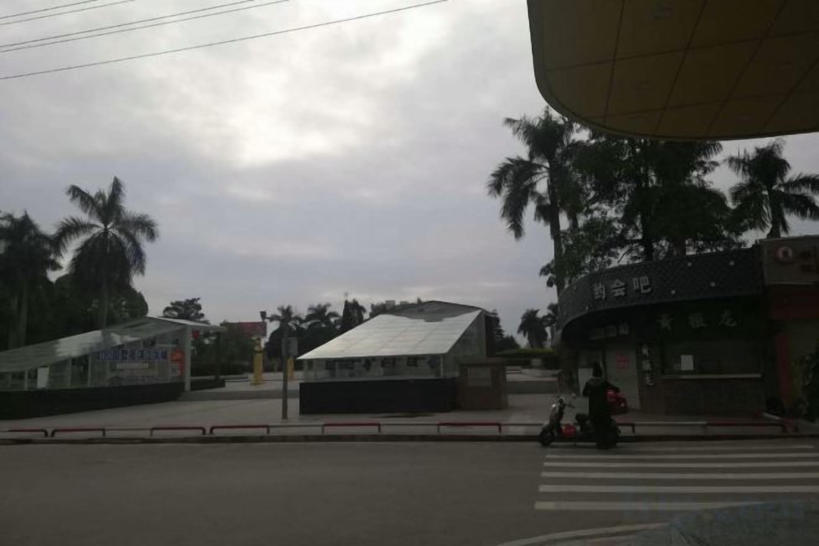 A street view with a bus stop, a pedestrian crossing, and a building with a sign.
