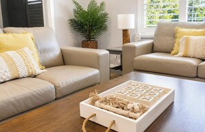 A living room with two beige sofas, a wooden coffee table with a decorative centerpiece, and a potted plant. - Castaway at Pelican – Relaxed, Pet Friendly Stay Near Lake And Beach (Pelican)