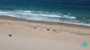 A beach with a sandy shore and a few umbrellas and beach chairs. - Castaway at Pelican – Relaxed, Pet Friendly Stay Near Lake And Beach (Pelican)
