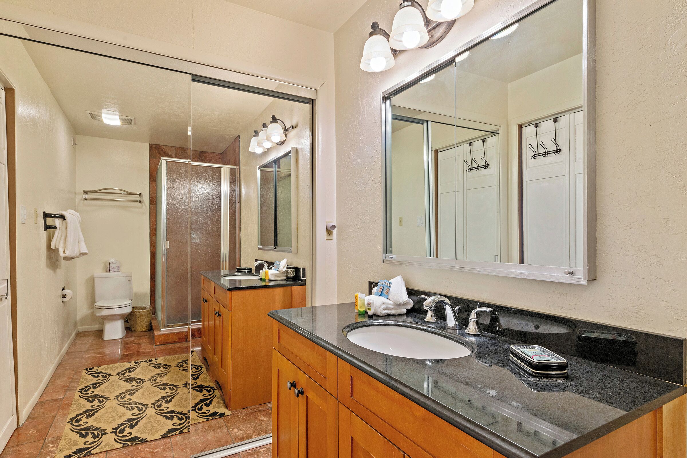 Une salle de bain avec un grand miroir, un lavabo et des toilettes.