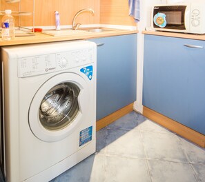A compact kitchen with a built-in washing machine, a microwave, and a sink.