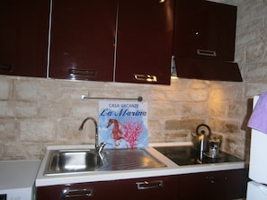 Uma cozinha com parede de pedra, uma pia e uma placa com a inscrição 'CASA VACANZE La Marina'.