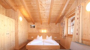 Une pièce de style cabane en bois, avec un lit, un canapé et une fenêtre avec des rideaux.