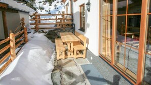 Un espace extérieur aménagé avec des sièges en bois et des marches en pierre menant à un bâtiment doté de grandes fenêtres.