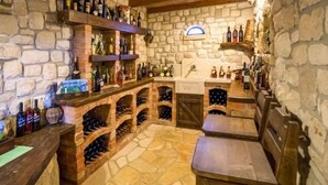 Une cave à vin aux murs de pierre, dotée d’étagères et de supports à bouteilles en bois.