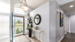A modern entryway with a glass door, a potted plant, a console table, and a mirror on the wall.
