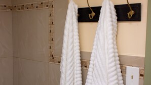 A bathroom with two white towels hanging on hooks, a shower area, and a tiled wall with a decorative border. - Centrally Located Boho Private BdR - 7 mi to beach (Naples)