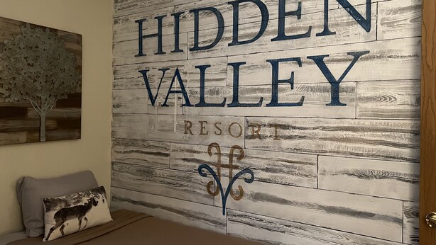 Un muro con il testo "HIDDEN VALLEY RESORT" in stile rustico in legno.