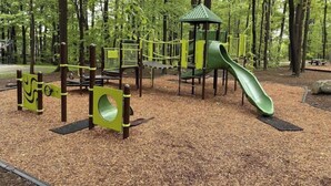 Un'area giochi con scivolo, strutture di arrampicata e un piccolo riparo.