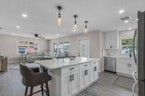 Una cocina moderna con armarios blancos, una isla central e iluminación colgante.