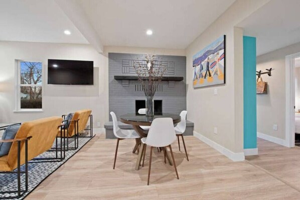 A modern dining area with a central table, white chairs, and a grey accent wall.