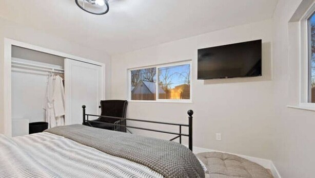 A bedroom with a bed, a chair, a TV, and a window with a view. - SuperChic Farmhouse*Old Town Arvada*LightRail*Dogs (Arvada)
