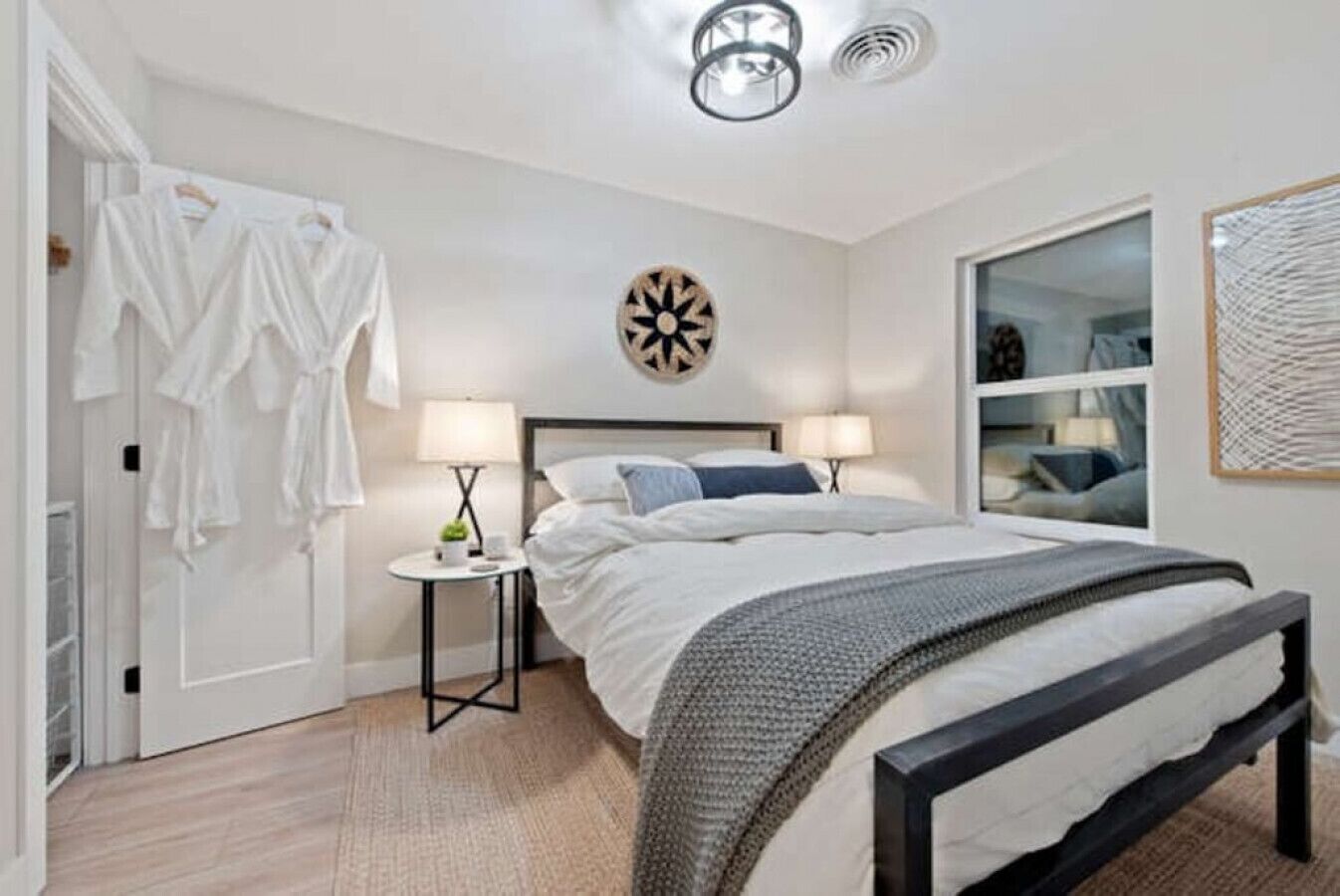 Une chambre à coucher comprenant un lit, des tables de chevet, une armoire, un miroir et une horloge murale.