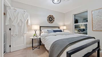 Une chambre à coucher comprenant un lit, des tables de chevet, une armoire, un miroir et une horloge murale.