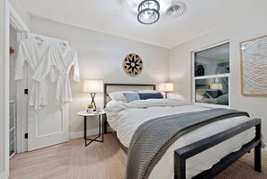Une chambre à coucher comprenant un lit, des tables de chevet, une armoire, un miroir et une horloge murale.