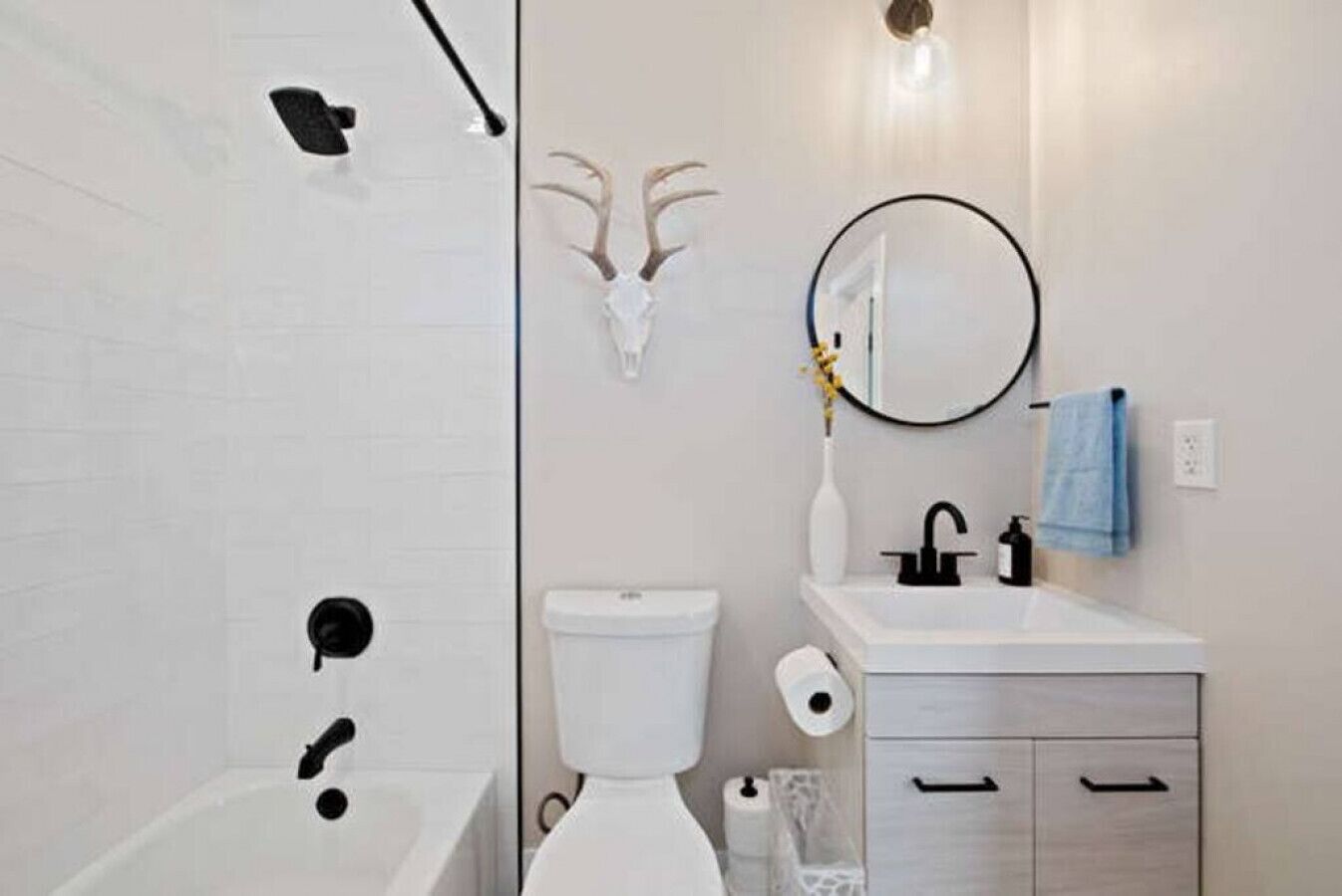 A bathroom with a white bathtub, a toilet, a sink with a mirror, and a towel rack.