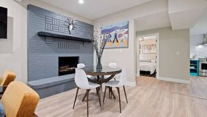 A modern living room with a fireplace, a dining table with chairs, and a painting on the wall. - SuperChic Farmhouse*Old Town Arvada*LightRail*Dogs (Arvada)