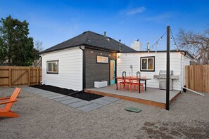 A single-story house with a patio area, a barbecue grill, and outdoor seating.