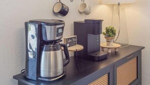 A coffee station with a coffee maker, a coffee machine, and a coffee bar sign.