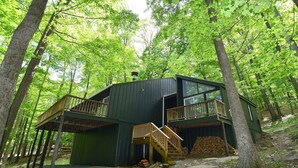 A cabin with a wooden deck and a staircase leading to a balcony. - Private hot tub, wooded, EV charger, 1-gig fiber internet (Berkeley Springs)
