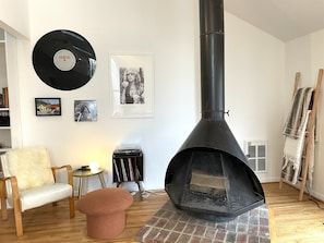A cozy living room with a fireplace, a vinyl record, and framed pictures on the wall. - Private hot tub, wooded, EV charger, 1-gig fiber internet (Berkeley Springs)