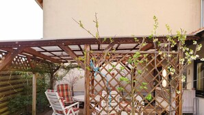 A covered patio area with a wooden pergola, a table, and two chairs. - Large bright vacation apartment_only for private guests_ no fitters (St. Leon-Rot)