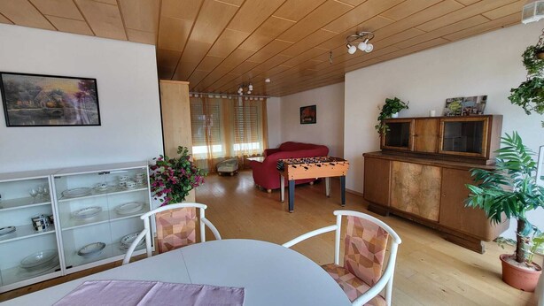 A cozy living room with a wooden ceiling, a red sofa, a foosball table, and a TV on a wooden cabinet. - Large bright vacation apartment_only for private guests_ no fitters (St. Leon-Rot)