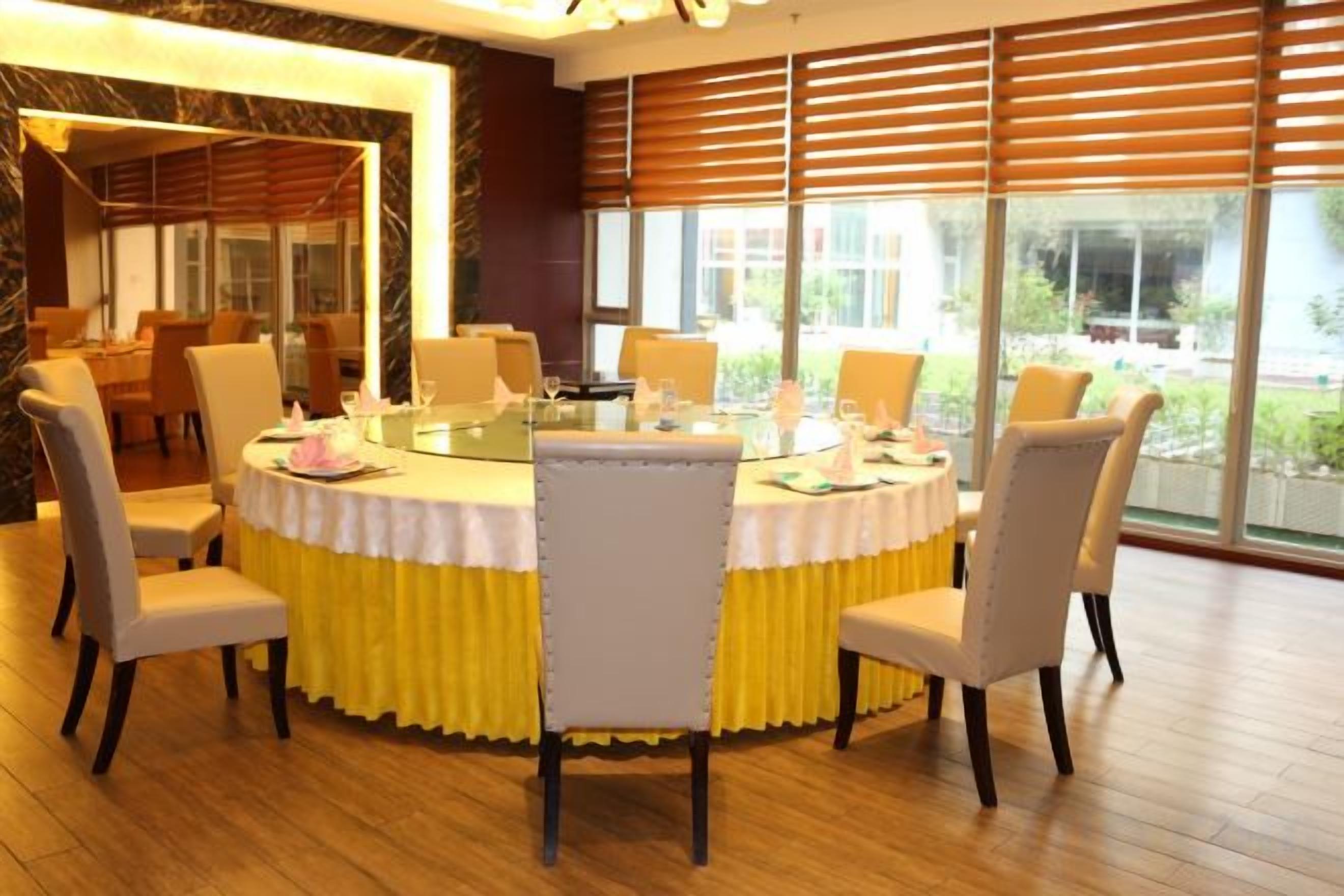 A conference room with a round table, chairs, and a view through large windows.