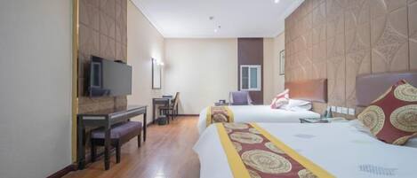 A hotel room with two beds, a desk with a chair, a television, and a window.