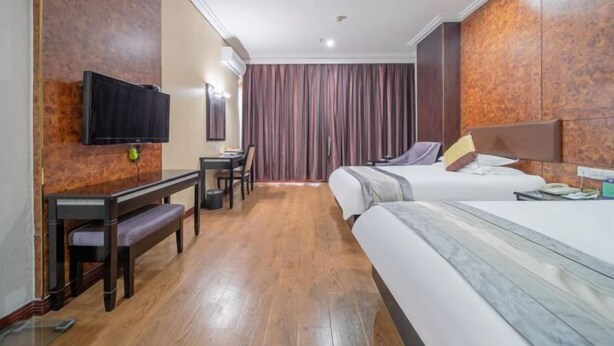 A hotel room with two beds, a desk, a chair, a television, and a curtain.