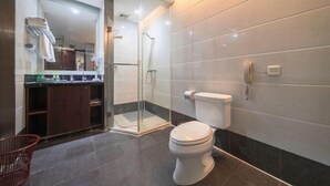 A modern bathroom with a glass-enclosed shower, a toilet, and a sink area with a towel rack.