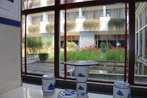 A room with a large window, a tiled floor, and a table with decorative items. - Rongma Hotel (Lianshui)