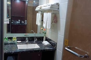 A bathroom with a marble sink, a mirror, a towel rack with folded towels, and a door with a handle. - Rongma Hotel (Huai'an)