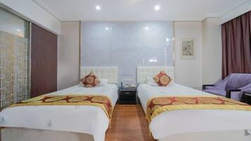 A hotel room with two beds, a nightstand, a chair, and a large mirror.