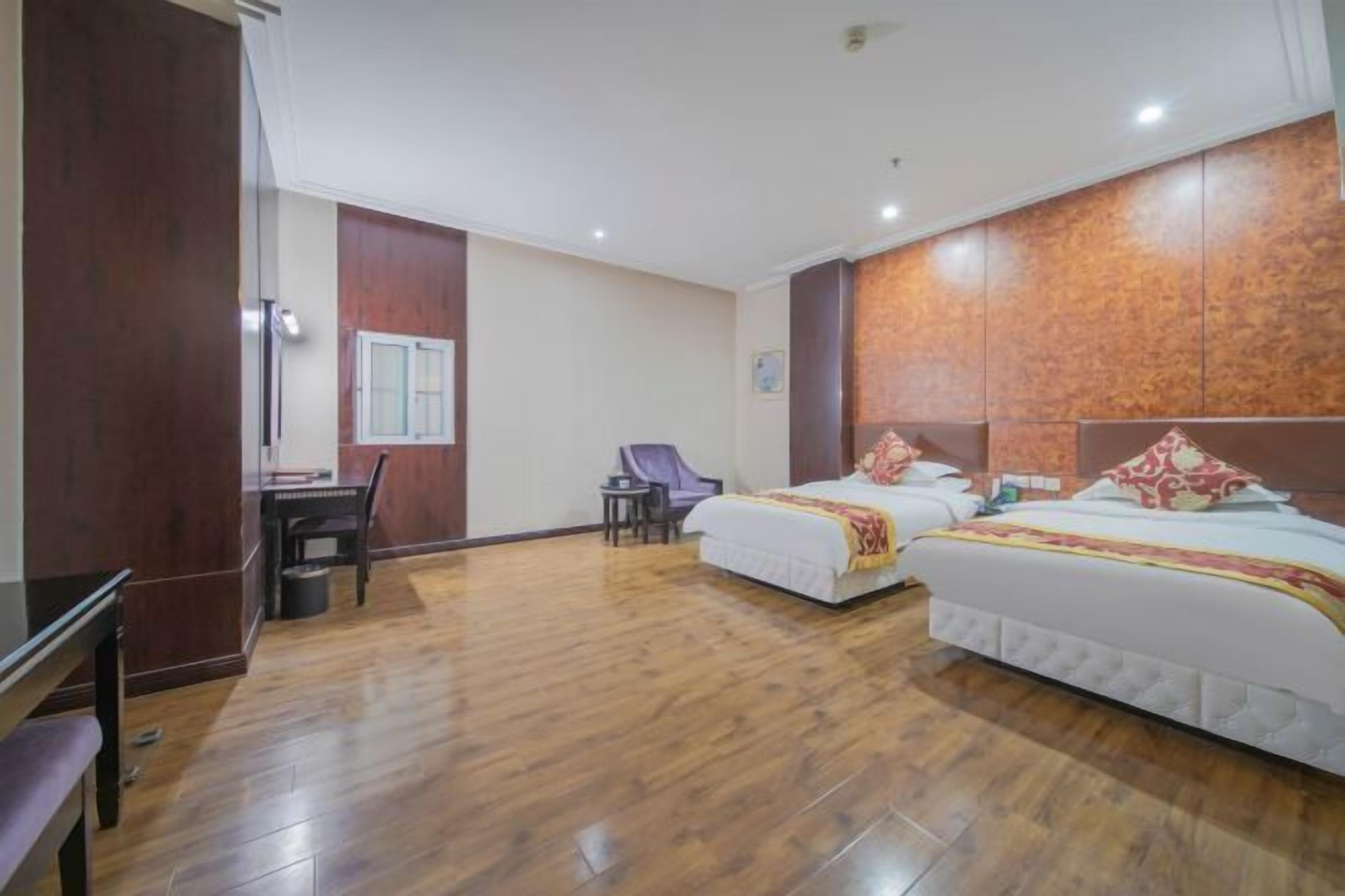 A hotel room with two beds, a desk, and a chair.