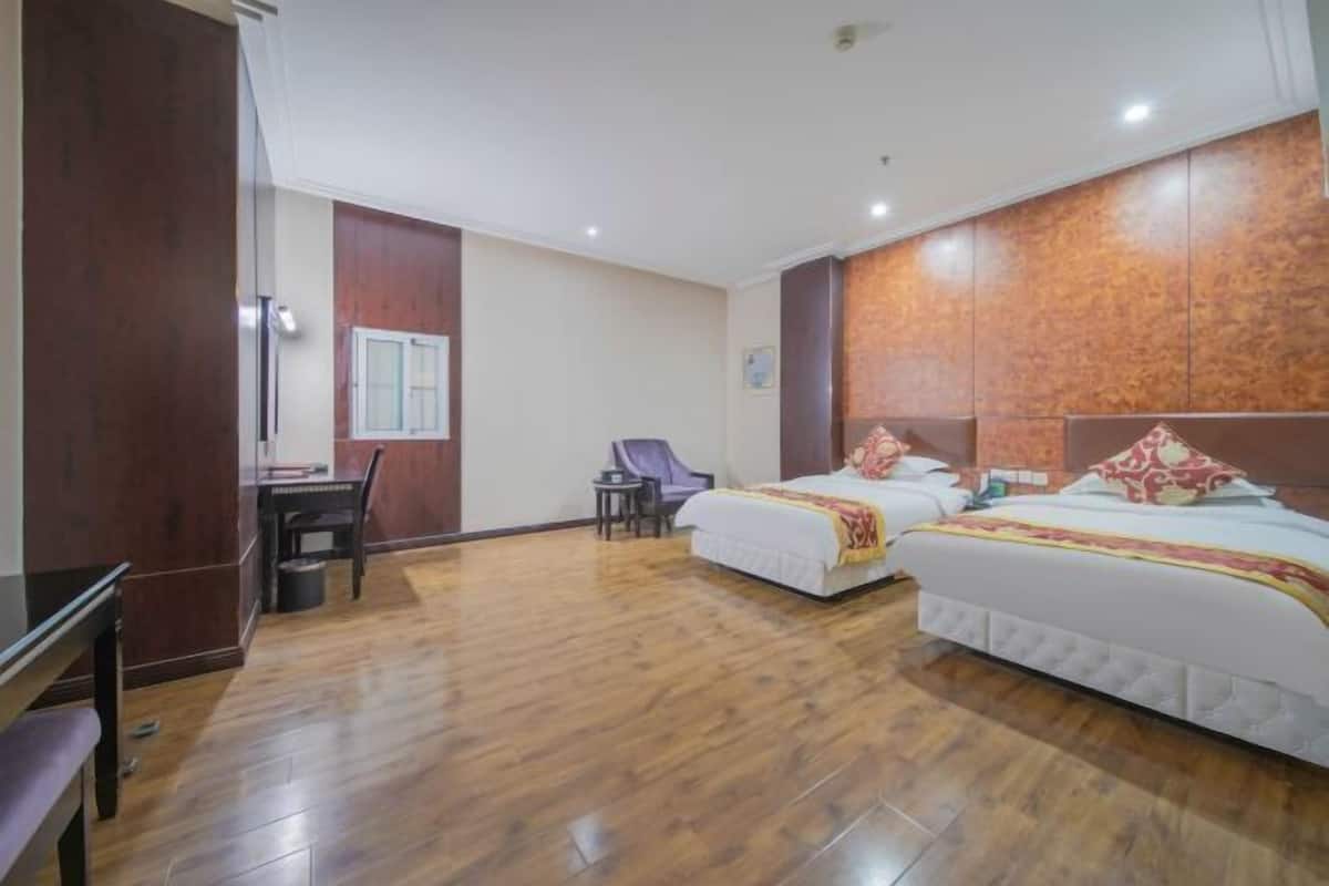 A hotel room with two beds, a desk, and a chair.