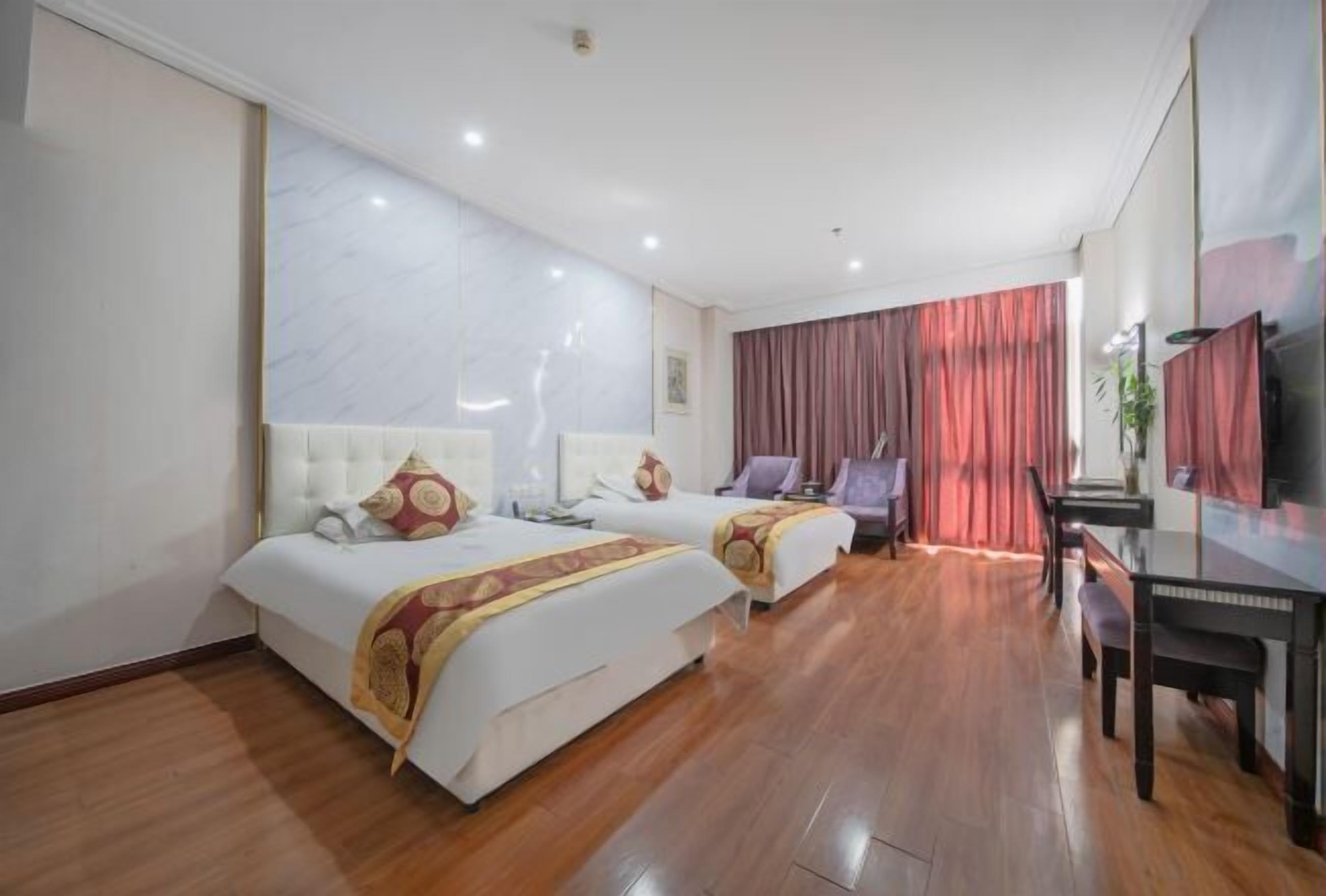 A hotel room with two beds, a desk, and a television.