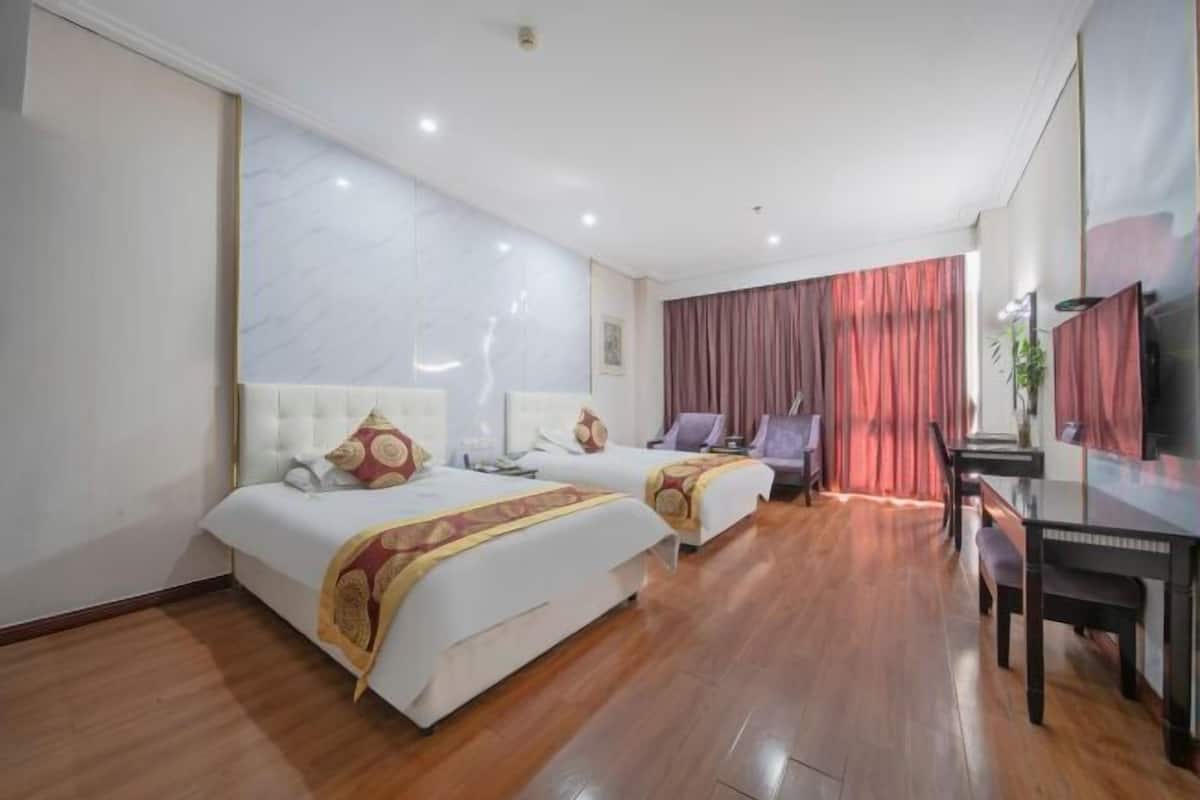 A hotel room with two beds, a desk, and a television.