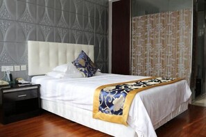 A neatly made bed with a white headboard, a decorative throw blanket, and a nightstand with a lamp.