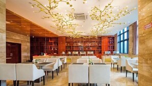 En rummelig restaurant med et moderne interiør, komplet med en central lysekrone, marmorgulv og forskellige siddepladser.