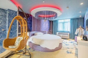 A modern bedroom with a hanging chair, a bed with a white headboard, and a circular ceiling light.