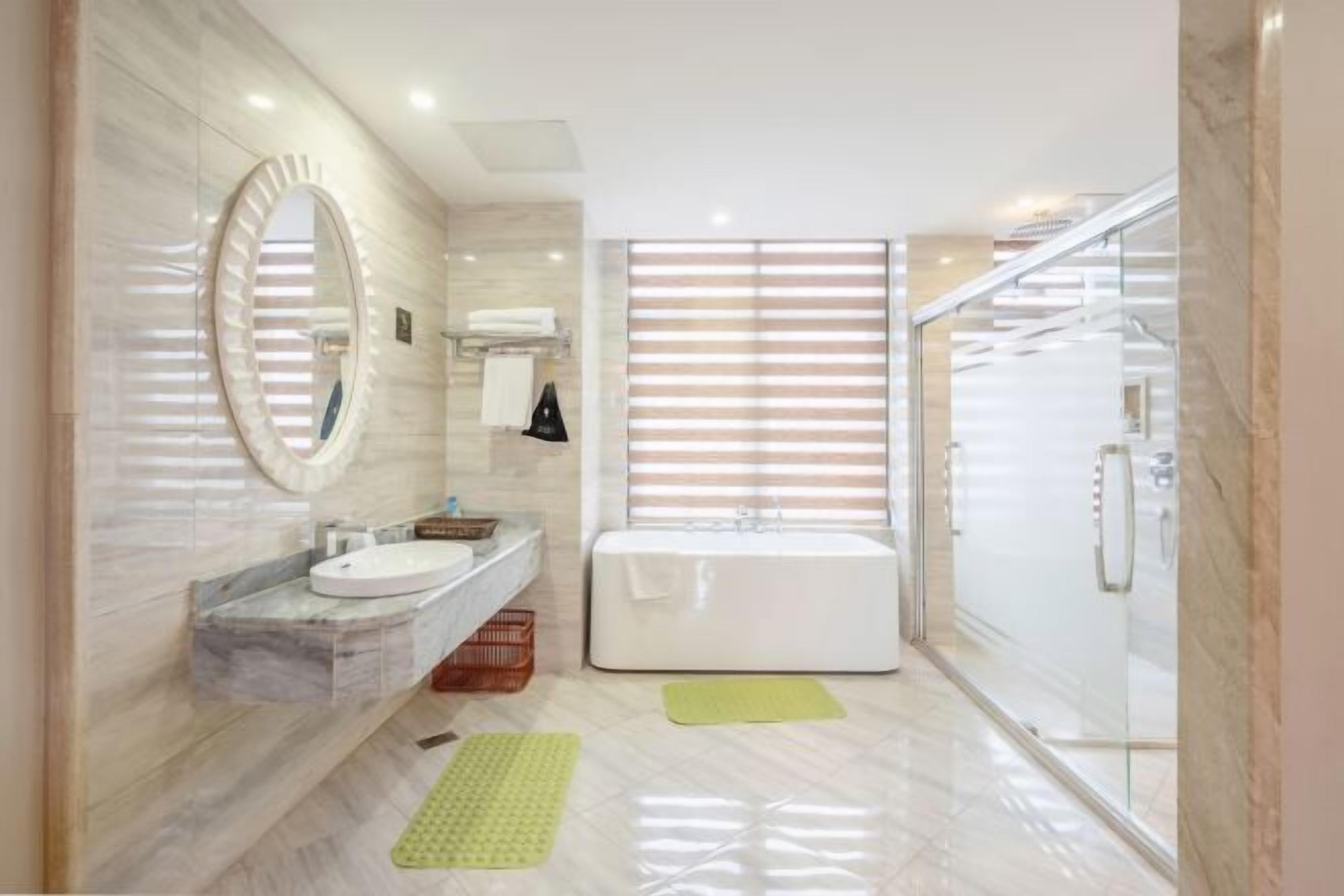 A modern bathroom with a marble vanity, a large mirror, a bathtub, and a glass shower enclosure.