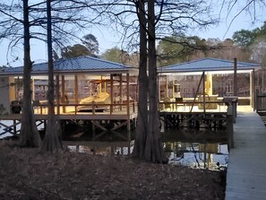 Un chalet situé au bord de l’eau, doté d’une terrasse couverte et d’un petit bateau amarré à proximité.