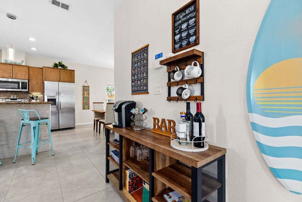 A modern kitchen with a bar area, including a coffee menu, mugs, and a refrigerator.