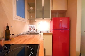 Une cuisine compacte avec un plan de travail en bois, un réfrigérateur rouge et un petit évier.