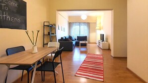Un salon moderne comprenant un coin repas, un canapé, un téléviseur et une lampe.